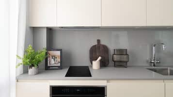 A modern kitchen with a built-in oven, a sink, and a potted plant.