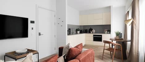 A modern living room with a sofa, a television, and a dining area with a table and chairs.
