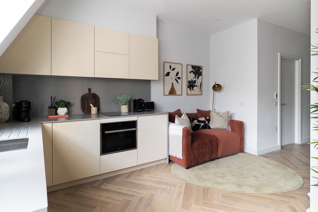 Una cocina moderna con electrodomésticos integrados, un comedor con sofá rojo y una sala de estar con alfombra blanca.