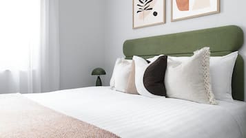 A neatly made bed with a green headboard, white bedding, and a textured throw blanket.
