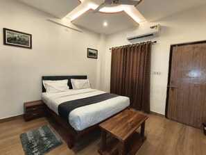 Ein Schlafzimmer mit Bett, Nachttischen, einer Bank, einem Kleiderschrank und einer Klimaanlage.