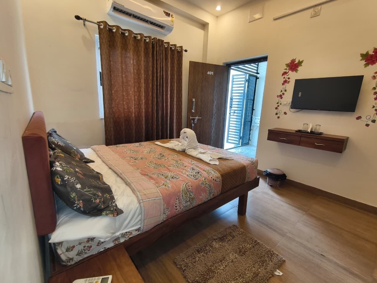 A bedroom with a bed, a TV, a wardrobe, and a window with curtains.