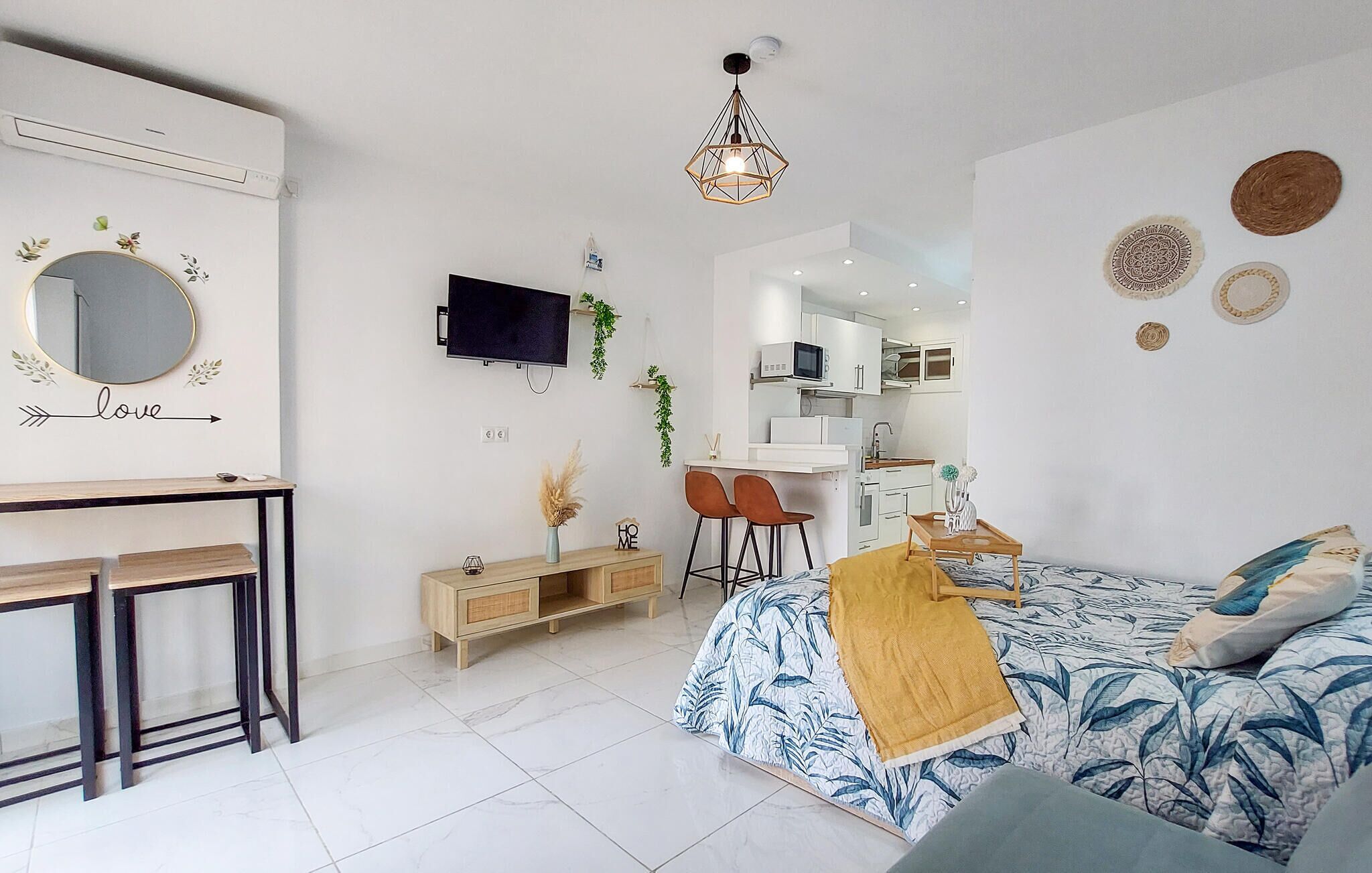 Ein modernes Schlafzimmer mit Bett, Schreibtisch, Fernseher und einer Küchenzeile.