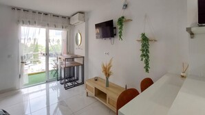 Una sala de estar moderna con comedor, televisor de pantalla plana y puerta corrediza de vidrio que da a un balcón.