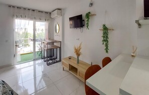 A modern living room with a dining area, a flat-screen TV, and a sliding glass door leading to a balcony. - Pet friendly apartment in Benalmadena with swimming pool (Benalmadena)