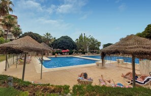A pool area with lounge chairs and thatched umbrellas. - Pet friendly apartment in Benalmadena with swimming pool (Benalmadena)