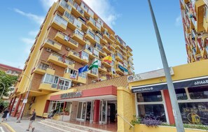 A multi-story hotel with balconies, a storefront with a sign, and a clear sky. - Pet friendly apartment in Benalmadena with swimming pool (Benalmadena)