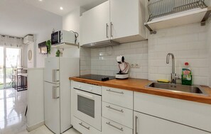 A modern kitchen with white cabinetry, a stainless steel sink, and a built-in oven. - Pet friendly apartment in Benalmadena with swimming pool (Benalmadena)