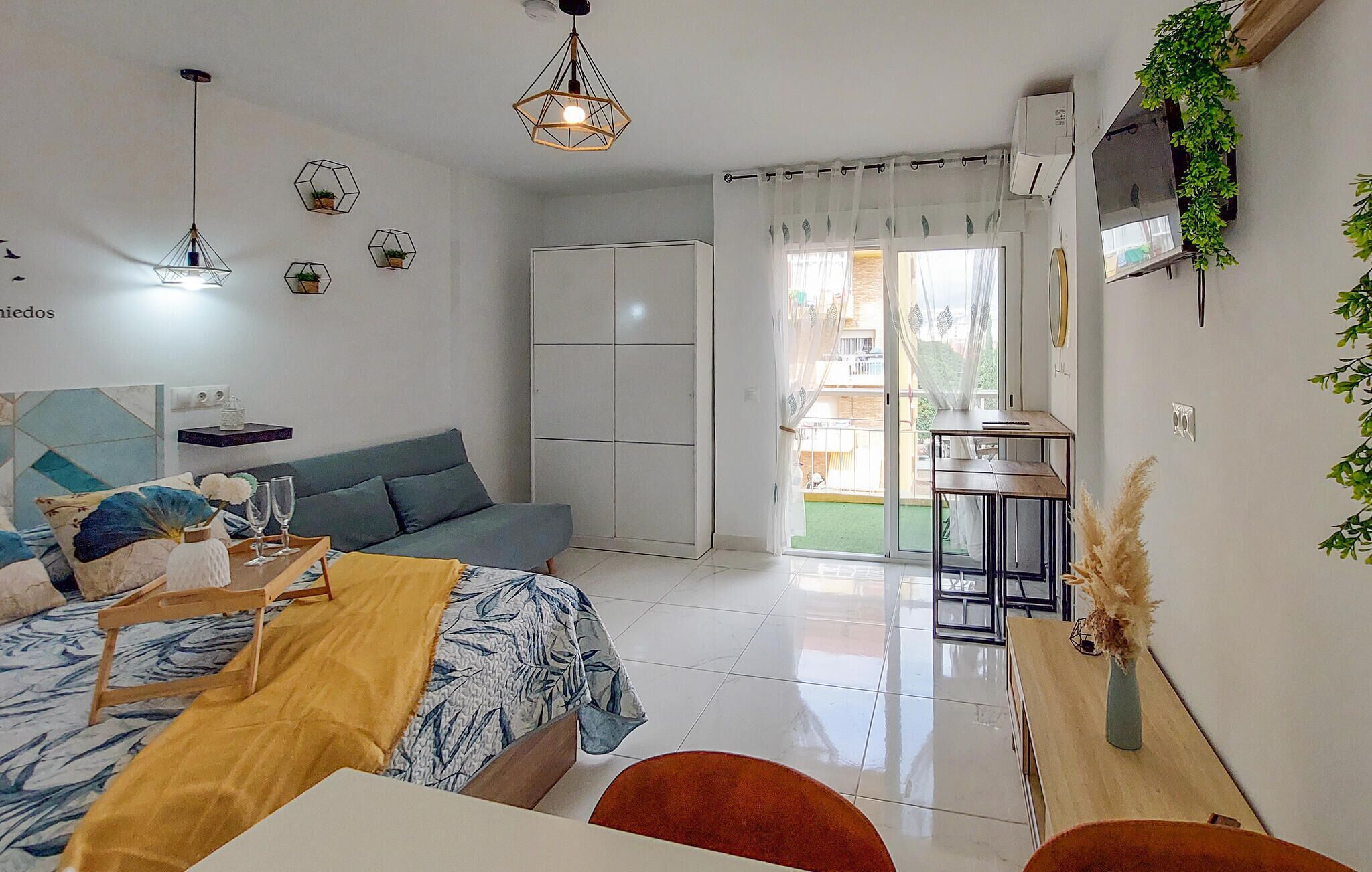 Ein modernes Schlafzimmer mit Bett, Sofa, Esstisch und Küchenzeile.
