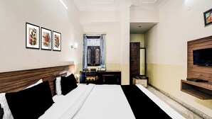 A hotel room with a large bed, a flat-screen TV, a desk with a chair, and a bathroom visible through an open door. - Collection O Raja Park Jaipur (Jaipur)
