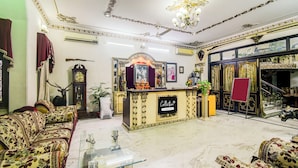 A spacious living room with a large sofa set, a decorative fireplace, and a chandelier. - Collection O Raja Park Jaipur (Jaipur)