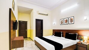 A hotel room with a bed, bedside tables, a nightstand, a lamp, and framed artwork on the wall. - Collection O Raja Park Jaipur (Jaipur)