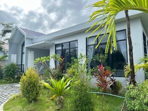 A modern house with a covered porch, large windows, and a well-maintained garden with various plants.