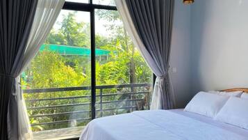 A bedroom with a large window, a bed, and a hanging light fixture.