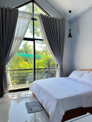 A bedroom with a large window, a bed, and a hanging light fixture.