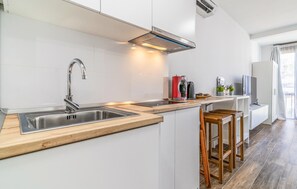 Eine moderne Küche mit weißen Schränken, Edelstahlgeräten und Holzbarhocker.