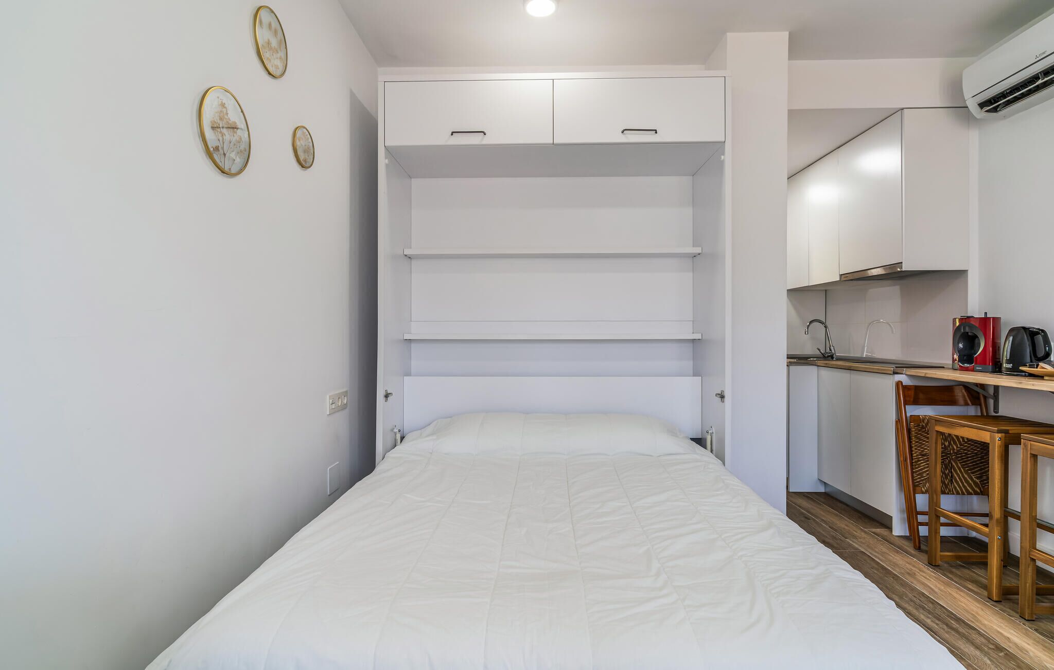 A compact room with a bed, a kitchenette, and a dining area.