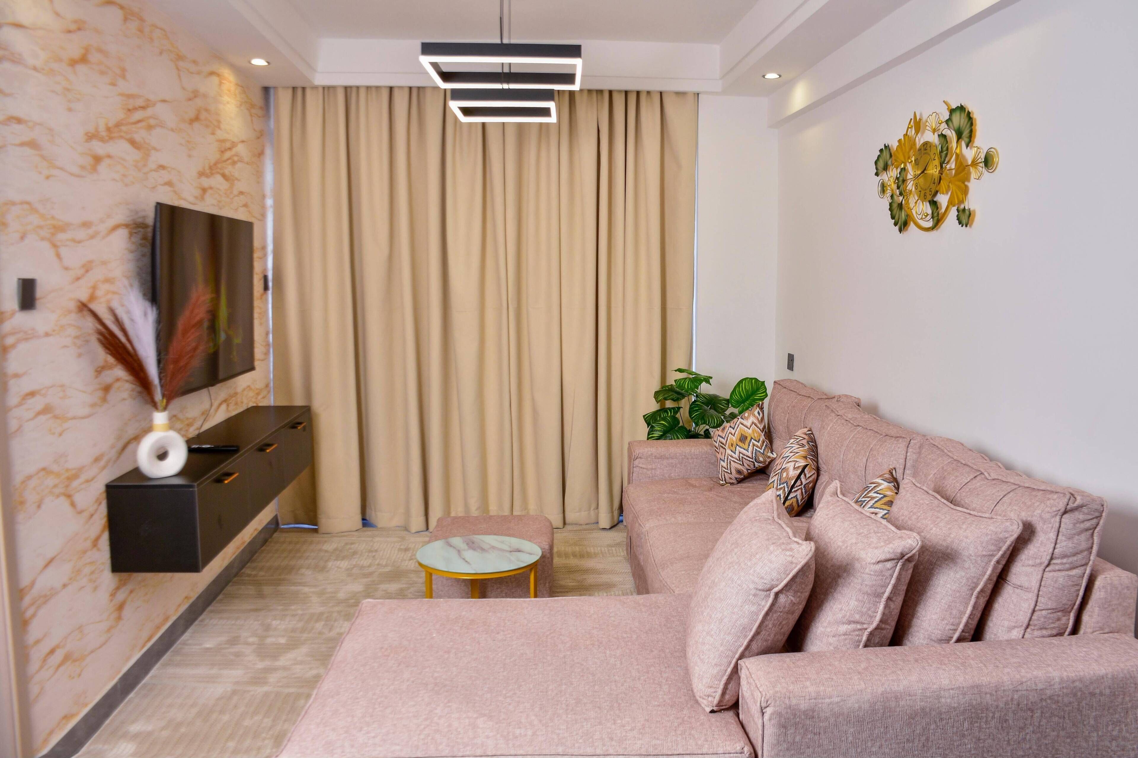 A modern living room with a sofa, a coffee table, a TV, and a decorative wall piece.