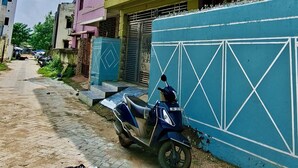 Un hotel con un cartel, una moto estacionada al frente y una pared azul con diseños geométricos.