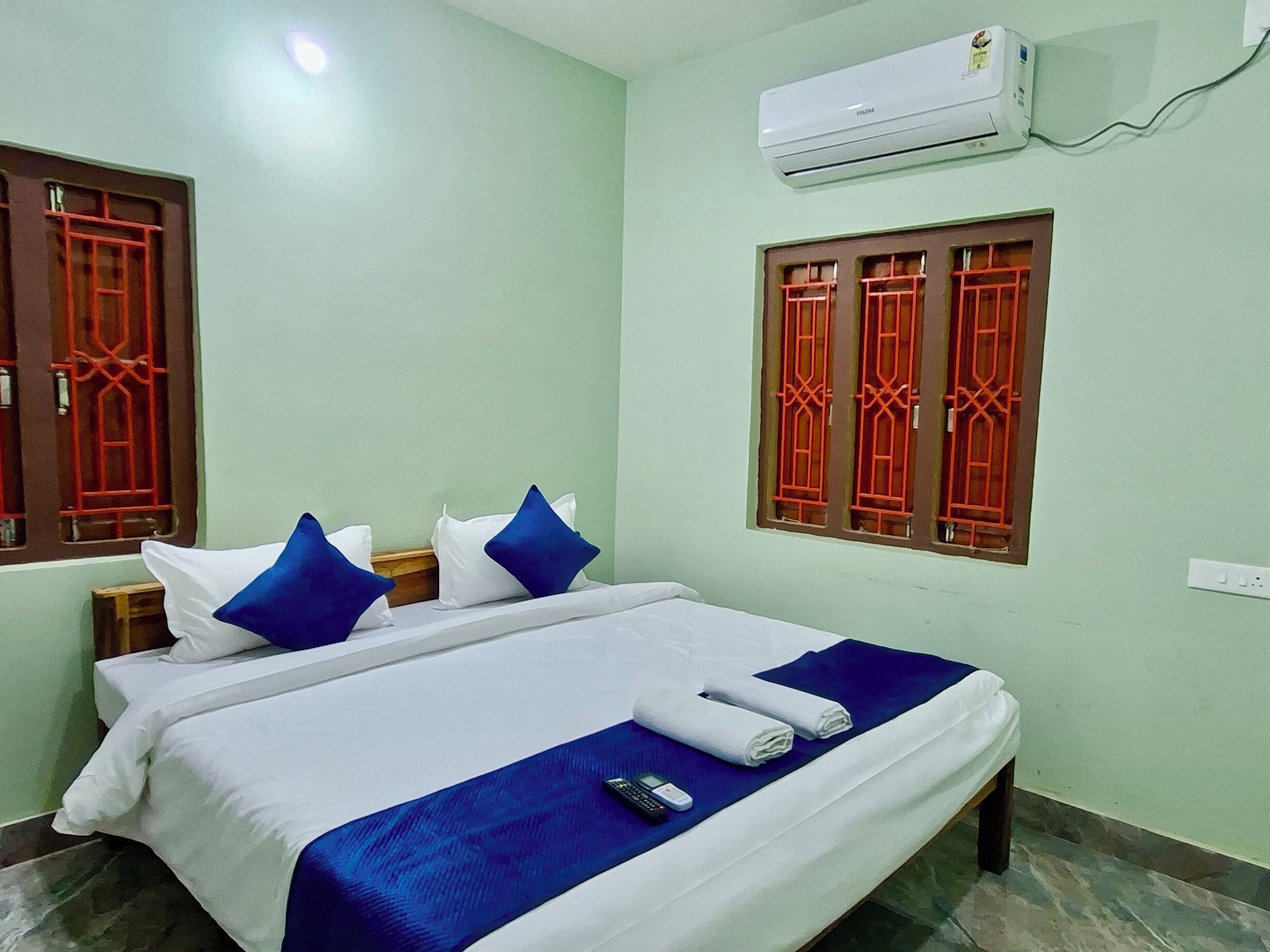 Habitación de hotel con cama, almohadas, un control remoto y una toalla doblada.