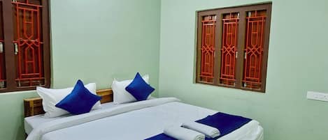 A hotel room with a bed, pillows, a remote control, and a folded towel.