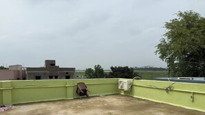 Una terraza en la azotea con un muro verde, un ventilador y una silla.