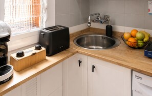 Een keuken met een broodrooster, een spoelbak, een fruitschaal en een koffiezetapparaat.