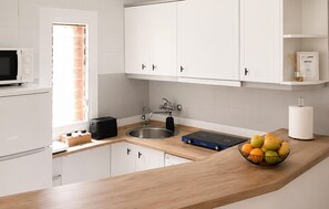 Eine moderne Küche mit weißen Schränken, einer Edelstahl-Spüle, einem Toaster und einer Obstschale auf der Arbeitsfläche.