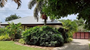 A house with a tiled roof, surrounded by lush greenery and a well-maintained lawn. - Baan Lompai Villa (Ao Nang)