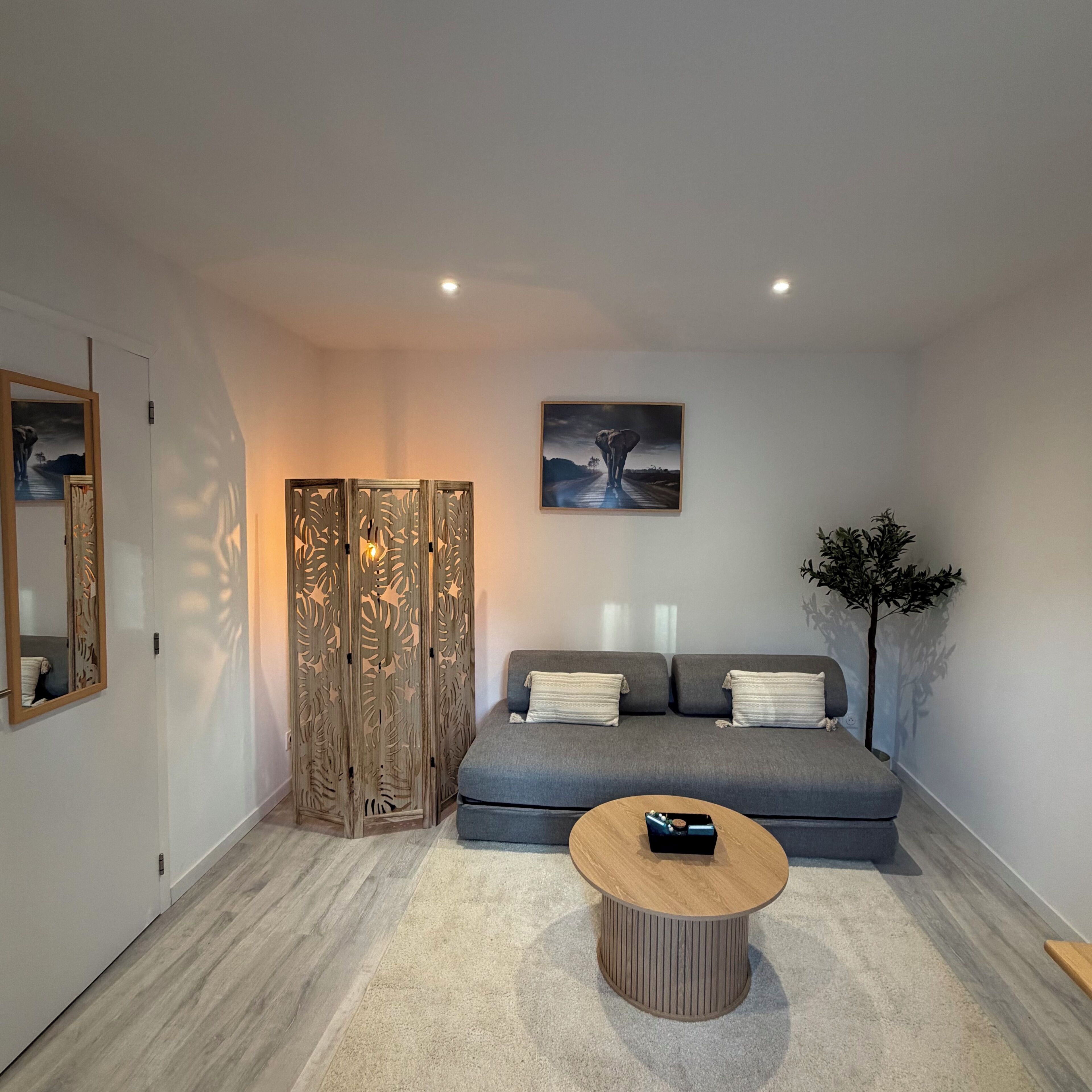 Ein modernes Wohnzimmer mit einem grauen Sofa, einem Holztisch und einem Bild an der Wand.