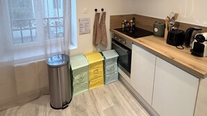 A compact kitchen with a window, a trash bin, and a stove. - 4★ Cozy Apartment in Contrexéville Thermal Baths (Contrexéville)