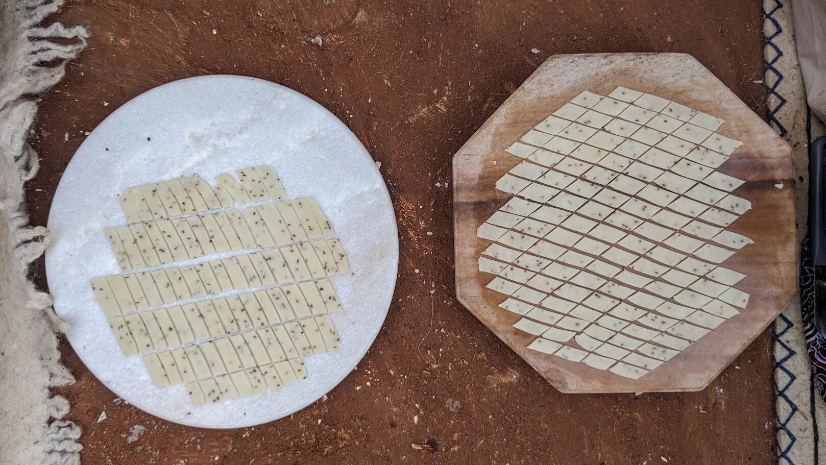 Two flatbreads with grid patterns on a textured surface.