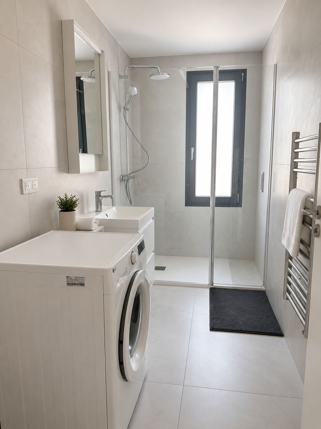 Een moderne badkamer met een ingebouwde wasmachine, een douchecabine en een grote spiegel.