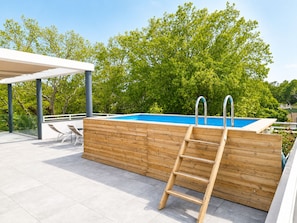 A swimming pool with a wooden deck, a ladder, and a covered seating area. - 3-bedroom apartment measuring 86 m², with a 70 m² rooftop terrace and a private pool (Saint-Raphaël)
