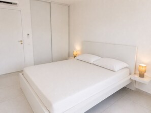 A minimalist bedroom with a single bed, bedside lamps, a wardrobe, and a door. - 3-bedroom apartment measuring 86 m², with a 70 m² rooftop terrace and a private pool (Saint-Raphaël)
