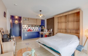 A compact bedroom with a bed, a desk, and a kitchenette. - Nice apartment in Lezardrieux with house sea view (Lezardrieux)