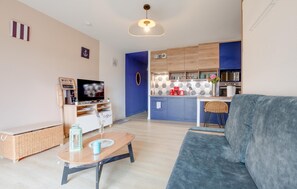 Ein modernes Wohnzimmer mit einer Couch, einem Fernseher, einem Couchtisch und einem Korbwäschesammler.