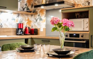 A dining table with black plates, clear glasses, and a vase with pink flowers. - Apartment in Lezardrieux (887) (Lezardrieux)