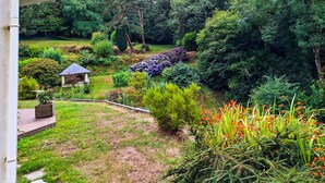 Un jardin agrémenté d’un kiosque, de diverses plantes et d’une terrasse en bois.