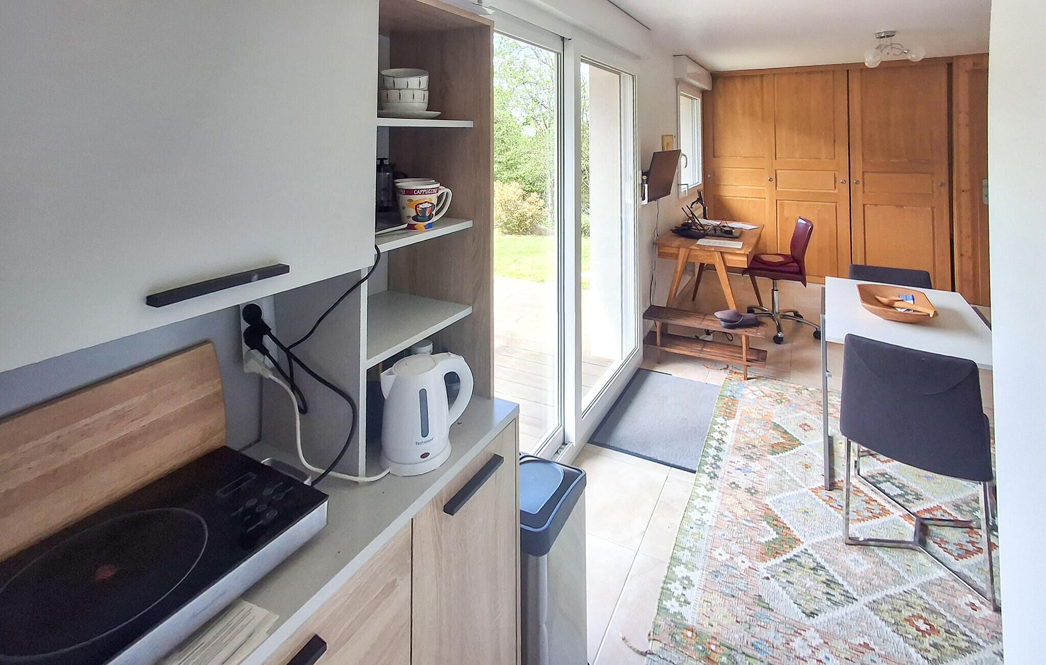 Una cocina compacta con estufa integrada, cafetera y un pequeño cubo de basura.