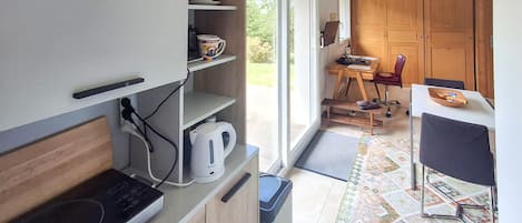 Una cocina compacta con estufa integrada, cafetera y un pequeño cubo de basura.