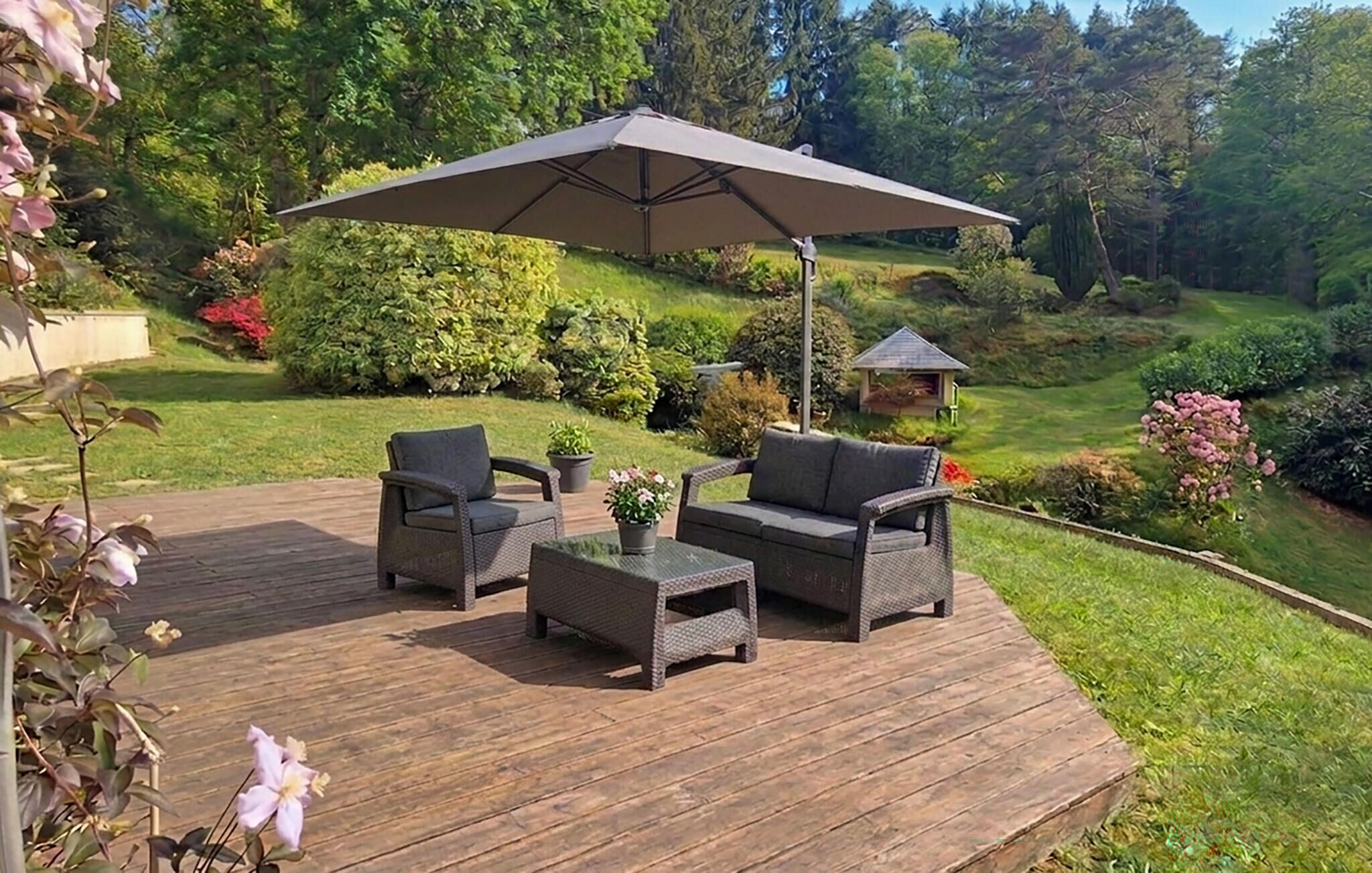 An outdoor patio with wicker furniture, a table, and a large umbrella.