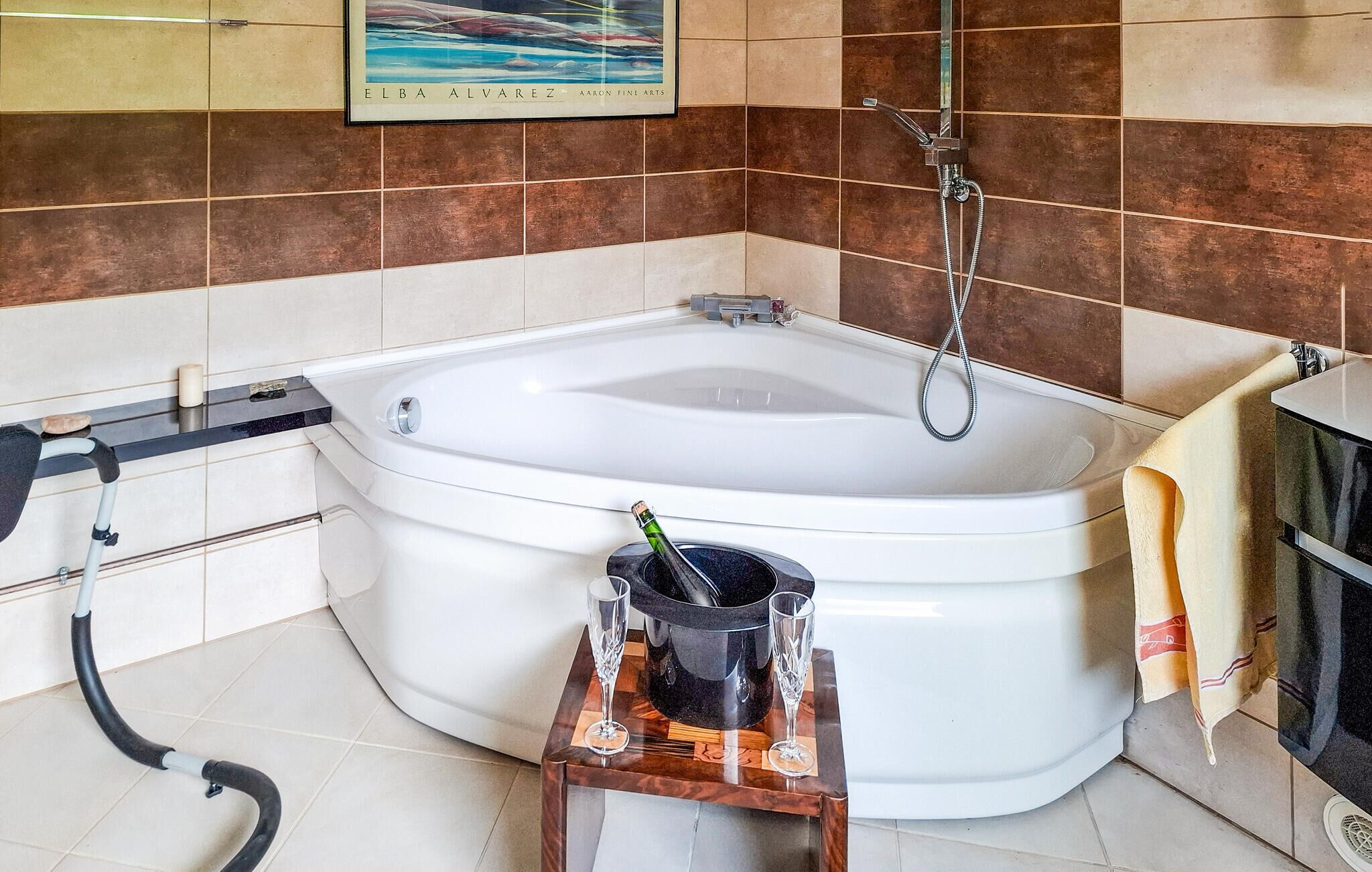 Een badkamer met een bad, een douche en een toilet. Er staat een stofzuiger, een emmer en twee glazen op een klein tafeltje.