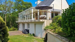 Une maison à deux étages avec un balcon, un garage et une pelouse.