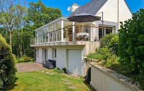 Ein zweistöckiges Haus mit Balkon, Garage und Rasenfläche.