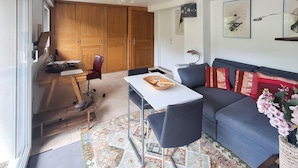 Un espace de vie compact comprenant un canapé, une table à manger et un coin cuisine.
