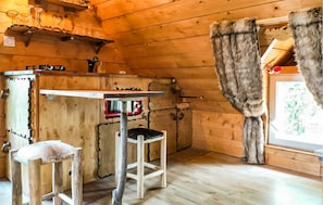 A rustic wooden cabin interior with a wooden table, a bar stool, and a fur-covered chair. - Gorgeous apartment in Rosporden (Rosporden)
