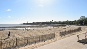 En strand med ett trästaket, en gångbana av betong och en klar himmel.
