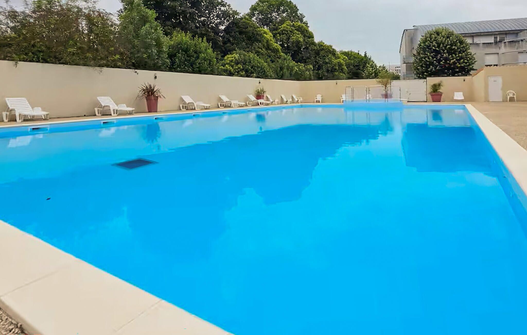 Ein Schwimmbecken mit Liegestühlen und Topfpflanzen.