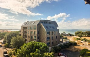 A modern building with a sloped roof, large windows, and a view of the sea.